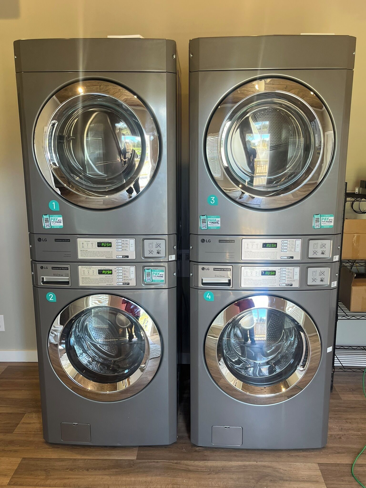 Twee commerciële wasmachines met bedieningspanelen, genummerd van 1 tot 4, in een ruimte met houten vloer.