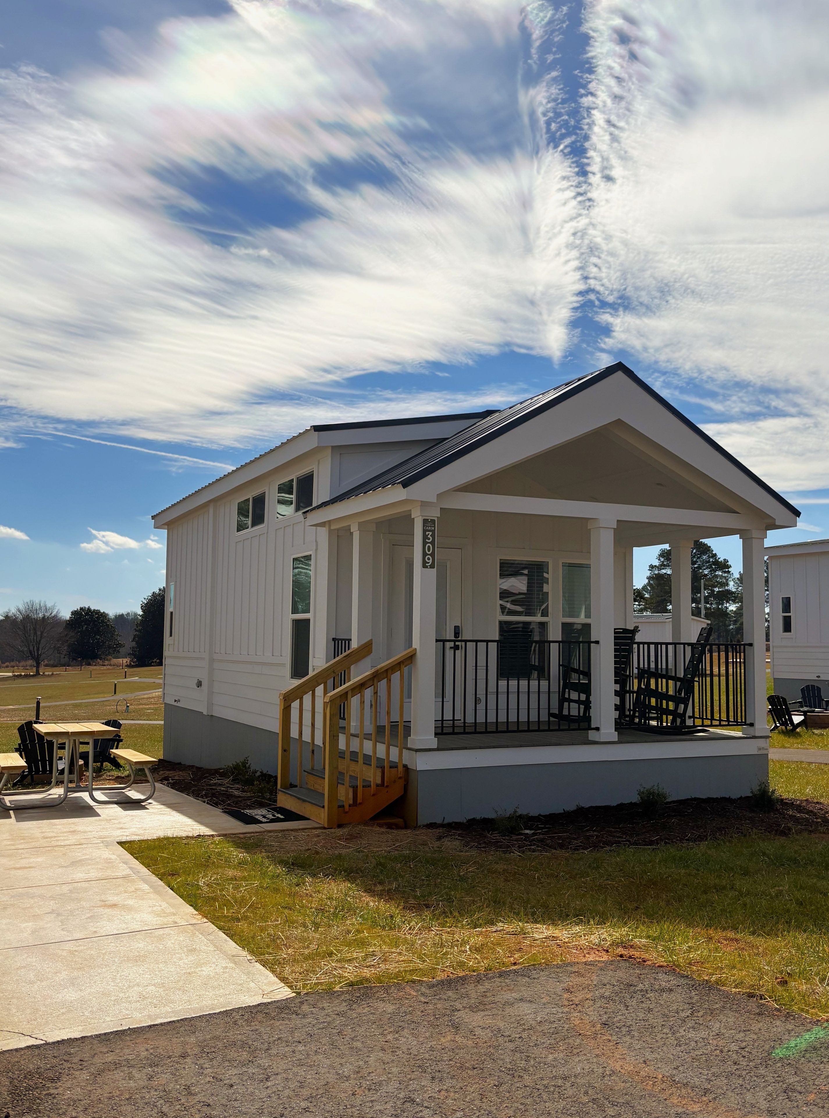 A single-story house with a porch, a staircase, and a small outdoor seating area.
