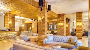 Un hall d’entrée spacieux avec des lambris en bois, des fauteuils confortables et un mur décoratif en pierre.