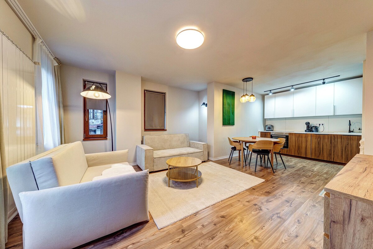 Een moderne woonkamer met een bank, salontafel en eethoek.