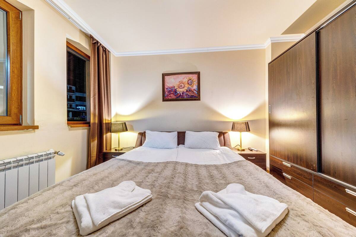 Una habitación de hotel con una cama grande, dos lámparas de noche, un cuadro en la pared y un armario.