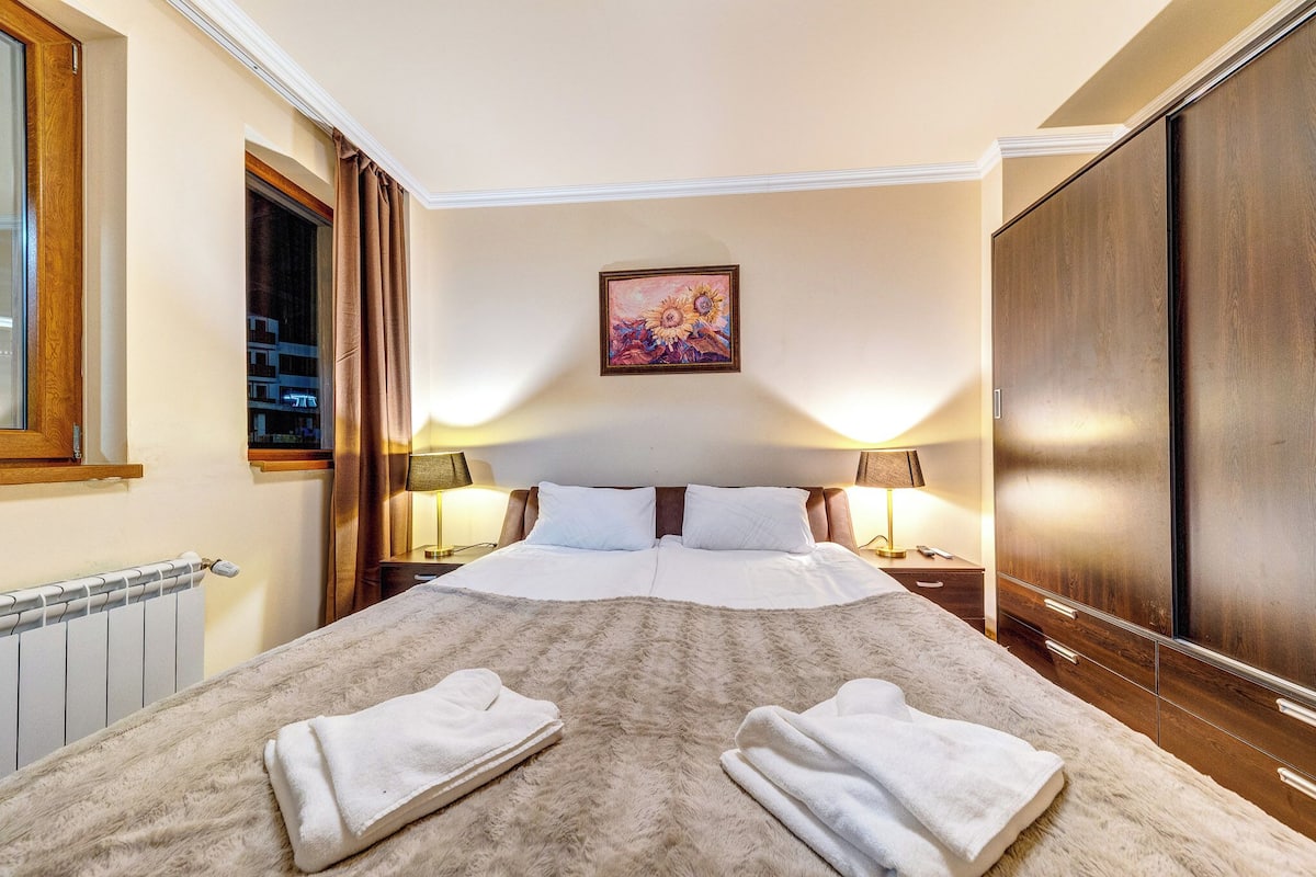 Una habitación de hotel con una cama grande, dos lámparas de noche, un cuadro en la pared y un armario.