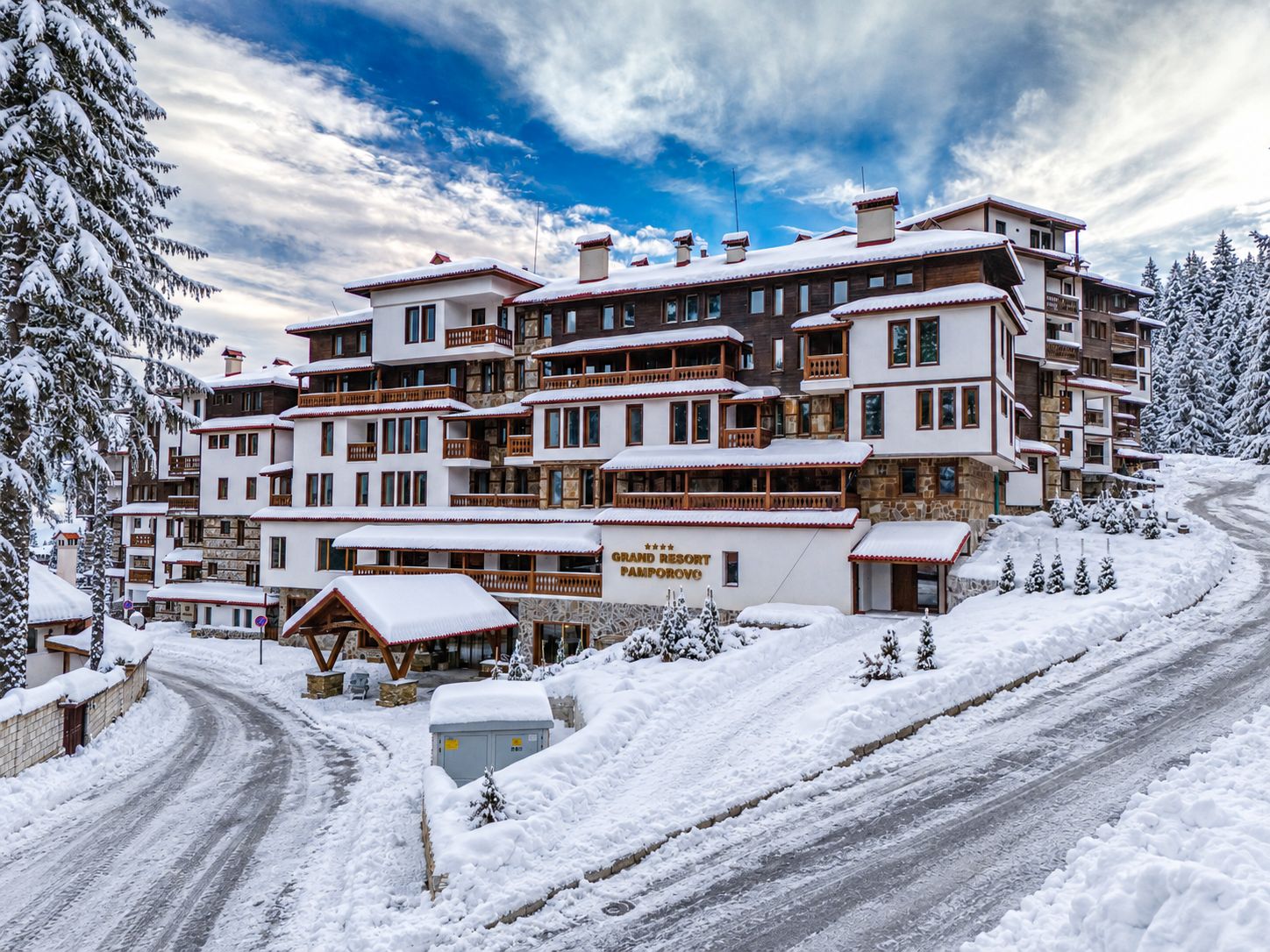 A multi-story hotel with balconies, a ski resort sign, and snow-covered surroundings.