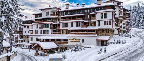 A multi-story hotel with balconies, a ski resort sign, and snow-covered surroundings.