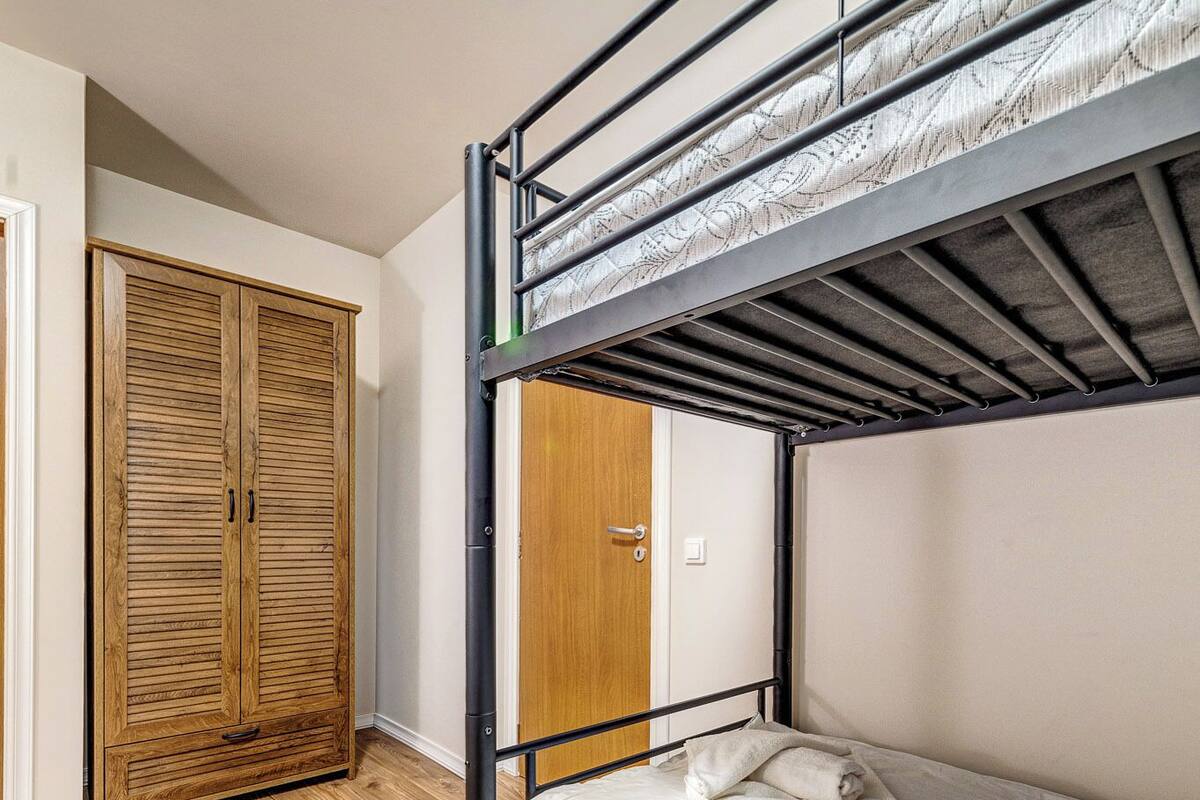 Una cama litera con un armario de madera y una puerta en una habitación con suelo de madera.