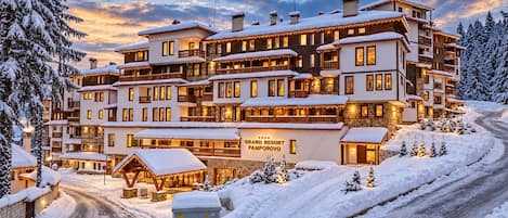A multi-story hotel with a snow-covered exterior, a visible sign indicating it is a resort, and a paved driveway leading to the entrance.