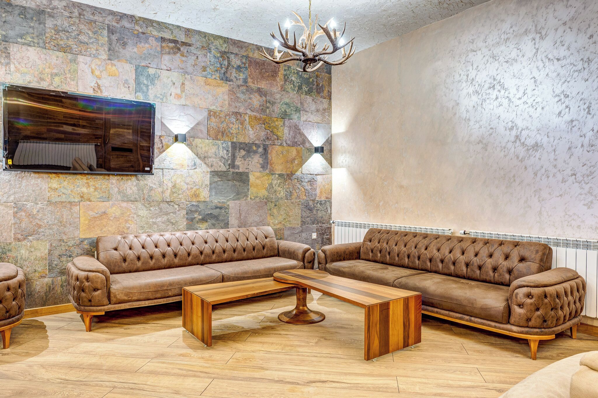 Un salon avec un canapé d’angle, une table basse en bois et un mur en pierre.