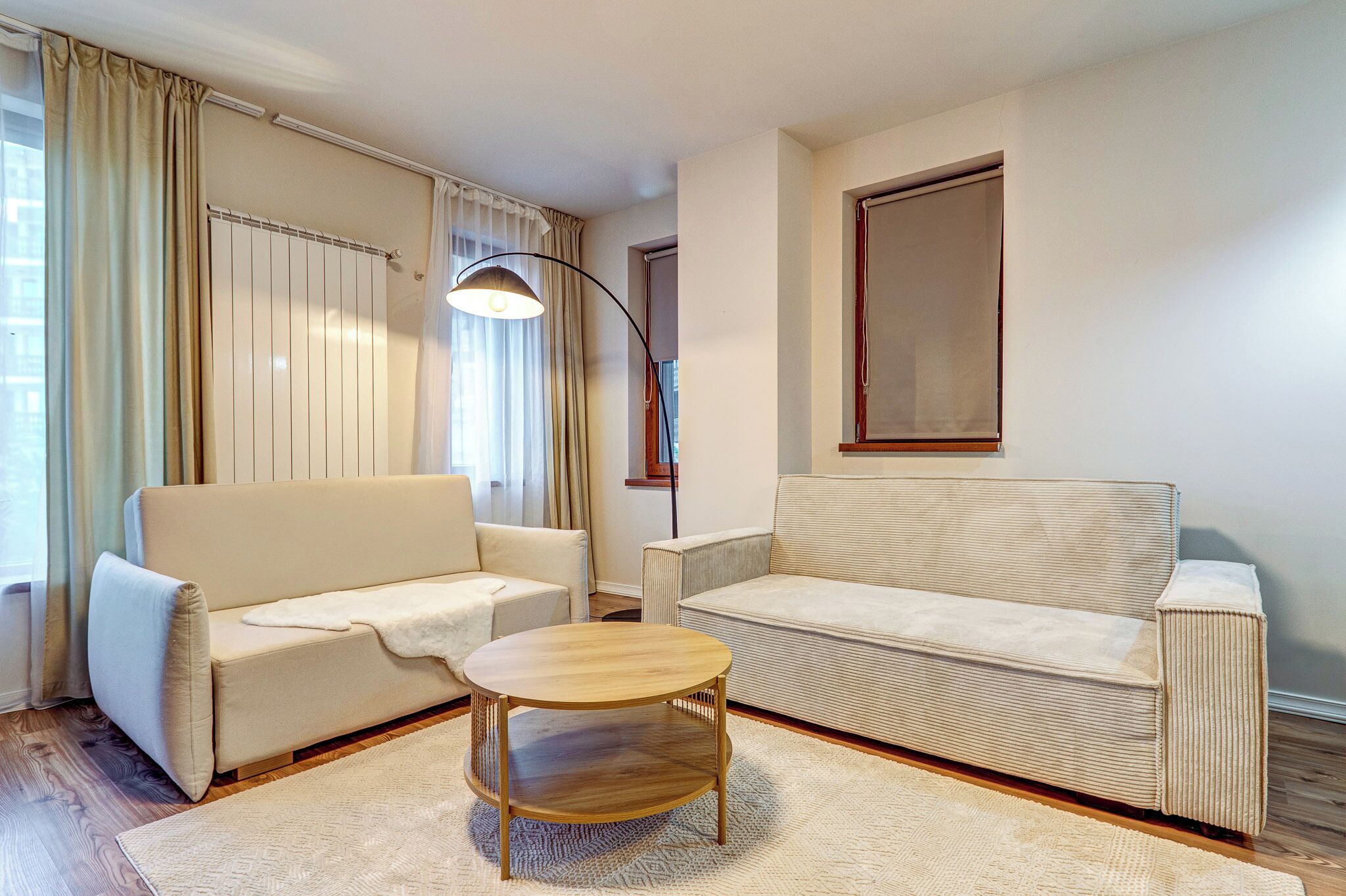 Una sala de estar con dos sofás, una mesa de centro redonda y una lámpara de pie.