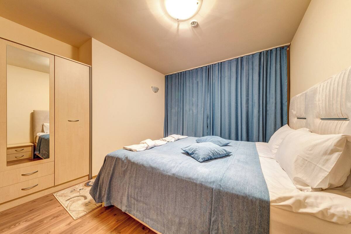 Un dormitorio con cama, armario, espejo y luz en el techo.