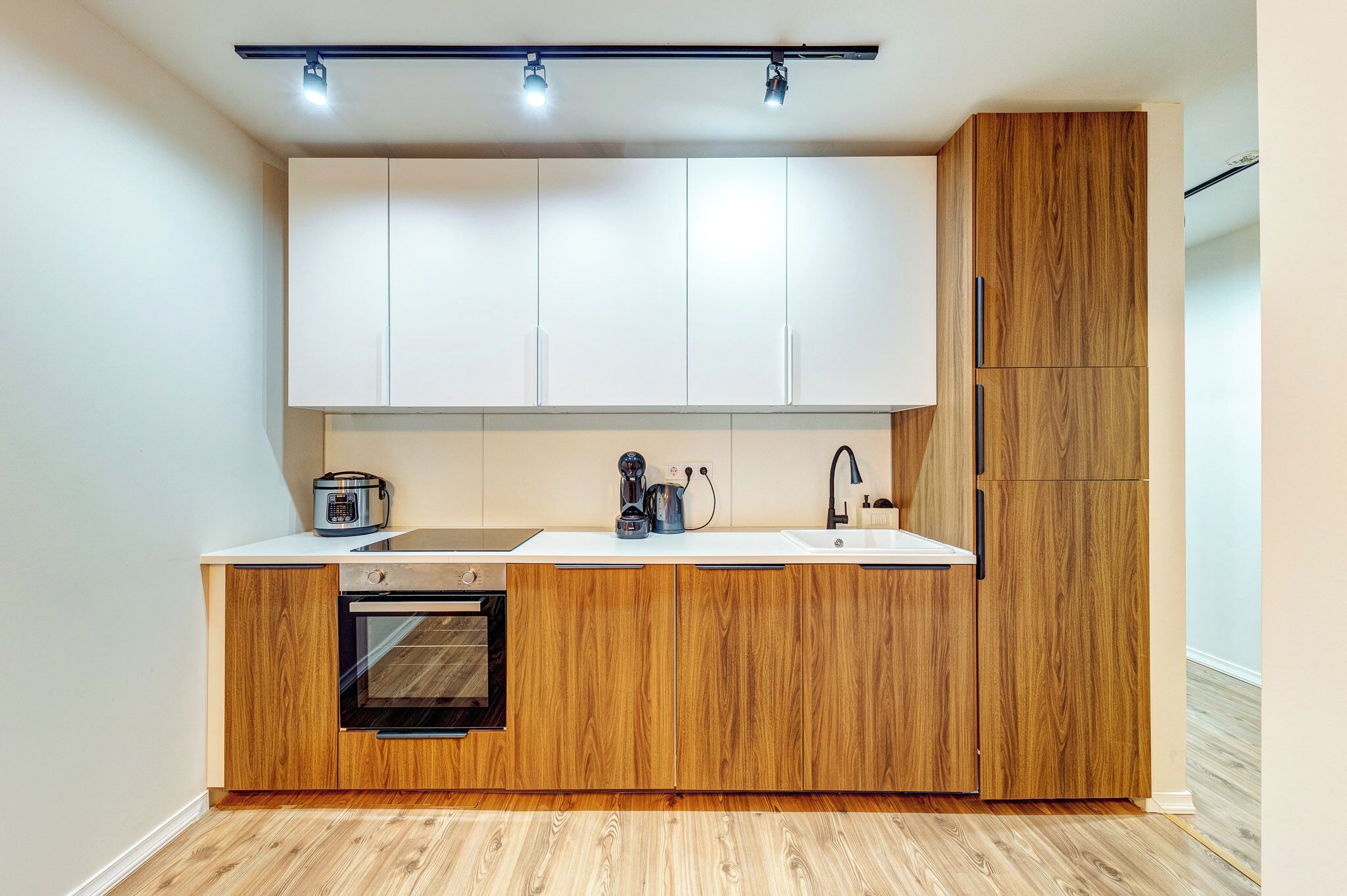 Una cocina moderna con armarios blancos, encimera de madera, horno empotrado y cafetera.