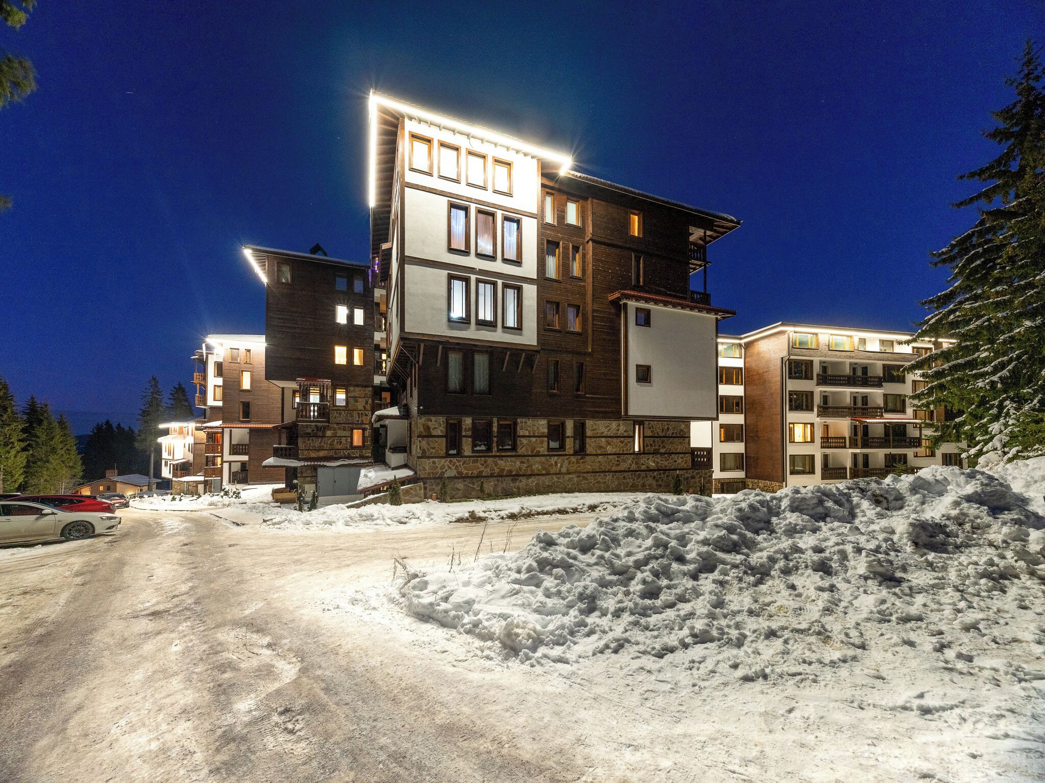A multi-story hotel with a stone facade, multiple balconies, and a snow-covered ground.