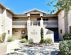 A building with a courtyard, numbered units, a cactus, and a balcony.
