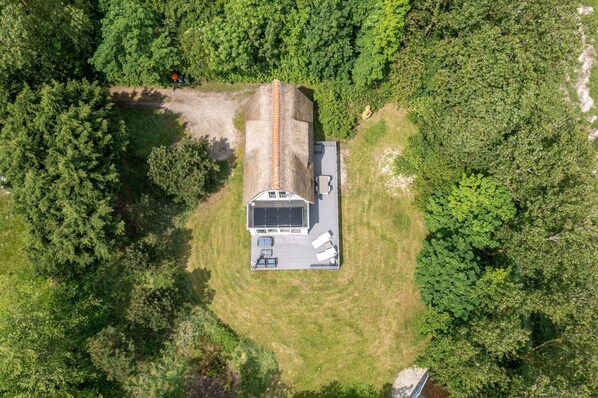 An aerial view of a single-story RV with a solar panel roof, surrounded by dense forest. - Charming Country House for 4 People (De Koog)