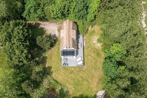 Vista aérea de una caravana de un nivel con paneles solares en el techo, rodeada de un bosque denso.