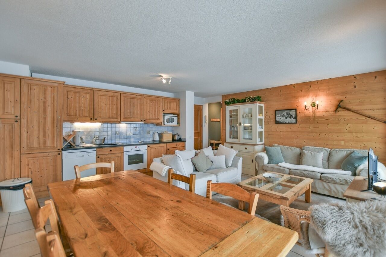Ein gemütliches Wohnzimmer mit einem Holzesstisch, weißen Sofas und einem Kamin.