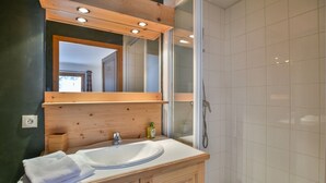 A modern bathroom with a wooden vanity, a large mirror, and a glass shower enclosure. - Pistes du Soleil C1 - Four Bedroom Apartment, Sleeps 8 (Le Grand Bornand)