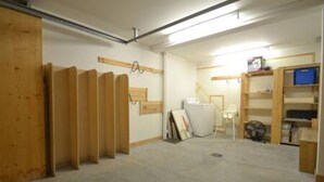 A room with a concrete floor, wooden paneling on one wall, and a white fan in the corner. - Chalet Mitoyen - Solar Est (Le Grand Bornand)