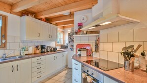 A kitchen with white cabinets, a red stove, and various kitchen utensils. - Chalet Mitoyen - Solar Est (Le Grand Bornand)
