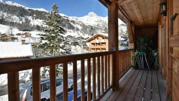 A wooden balcony with a view of snow-covered mountains and a clear sky. - Chalet Mitoyen - Solar Est (Le Grand Bornand)