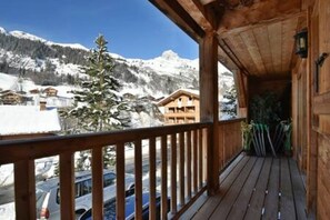 A wooden balcony with a view of snow-covered mountains and a clear sky. - Chalet Mitoyen - Solar Est (Le Grand Bornand)