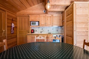 A wooden interior with a kitchen area, including cabinets, a microwave, and a sink.