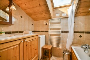 A wooden cabin bathroom with a skylight, a white sink, a towel rack, and a shower area. - Pistes du Soleil A15 (Le Grand Bornand)