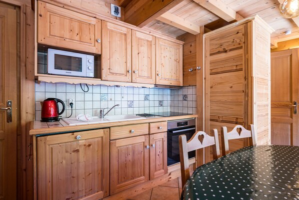 A wooden kitchen with a microwave, sink, and stove.