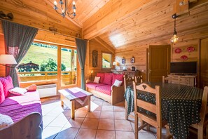 A cozy cabin interior with a sofa, dining table, and a view of the outdoors.