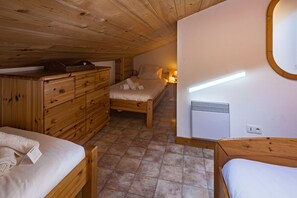 A compact room with a bed, a wooden dresser, and a small table.