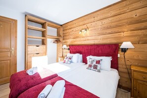 Ein Schlafzimmer mit Holzwänden, zwei Betten, einem Holzschrank und einem roten Kopfteil.