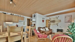 A cozy living area with wooden furniture, a fireplace, and a mounted clock. - Refuge Le Bardeau B2 (Le Grand Bornand)