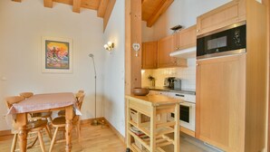 Una cocina con armarios de madera, un microondas y una mesa con sillas.
