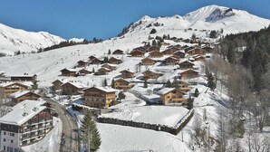 Un pueblo cubierto de nieve en la montaña con chalets de madera y una pista de esquí.