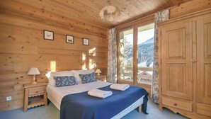 Quarto de cabana de madeira com cama, mesas de cabeceira e guarda-roupa.