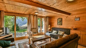 Um quarto acolhedor em estilo cabana, com decoração em madeira, um sofá, uma mesa de centro e uma televisão.