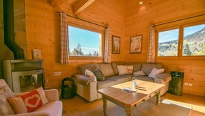 Un interior acogedor de cabaña con un sofá, una mesa de madera y una chimenea.