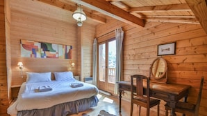 Camera da letto in una baita di legno, con un letto, una scrivania e una sedia.