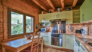 Una cucina in una casetta di legno, con tavolo, sedie, fornello, forno a microonde e pensili.
