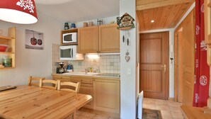 A kitchen with wooden cabinets, a wooden dining table, and a red hanging light fixture.
