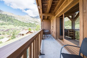 Un balcon en bois offrant une vue sur un paysage montagneux.
