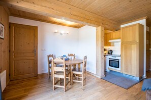 Un intérieur en bois comprenant un coin repas, une cuisine et une porte.