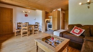 A cozy living room with wooden furniture, a glass coffee table, and a brown sofa. - Refuge Le Bardeau B4 (Le Grand Bornand)