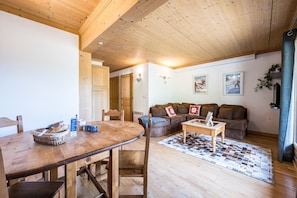 Un salon chaleureux avec un plafond en bois, une table à manger avec des chaises, un canapé et une table basse.