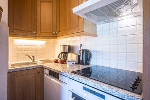 A kitchen with wooden cabinets, a stainless steel range hood, a built-in dishwasher, and a granite countertop.