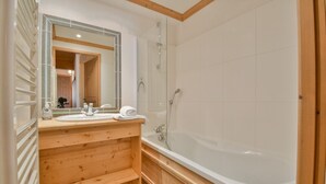 A bathroom with a wooden vanity, a large mirror, a bathtub, and a shower. - Refuge Le Bardeau B4 (Le Grand Bornand)