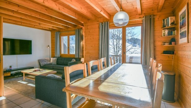 A wooden cabin with a dining table, sofa, and TV. - Chalet Mitoyen - Rosa (Le Grand Bornand)