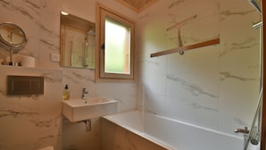A bathroom with a marble-tiled shower, a glass-enclosed bathtub, a sink with a mirror, and a window. - Chalet Mitoyen - Rosa (Le Grand Bornand)