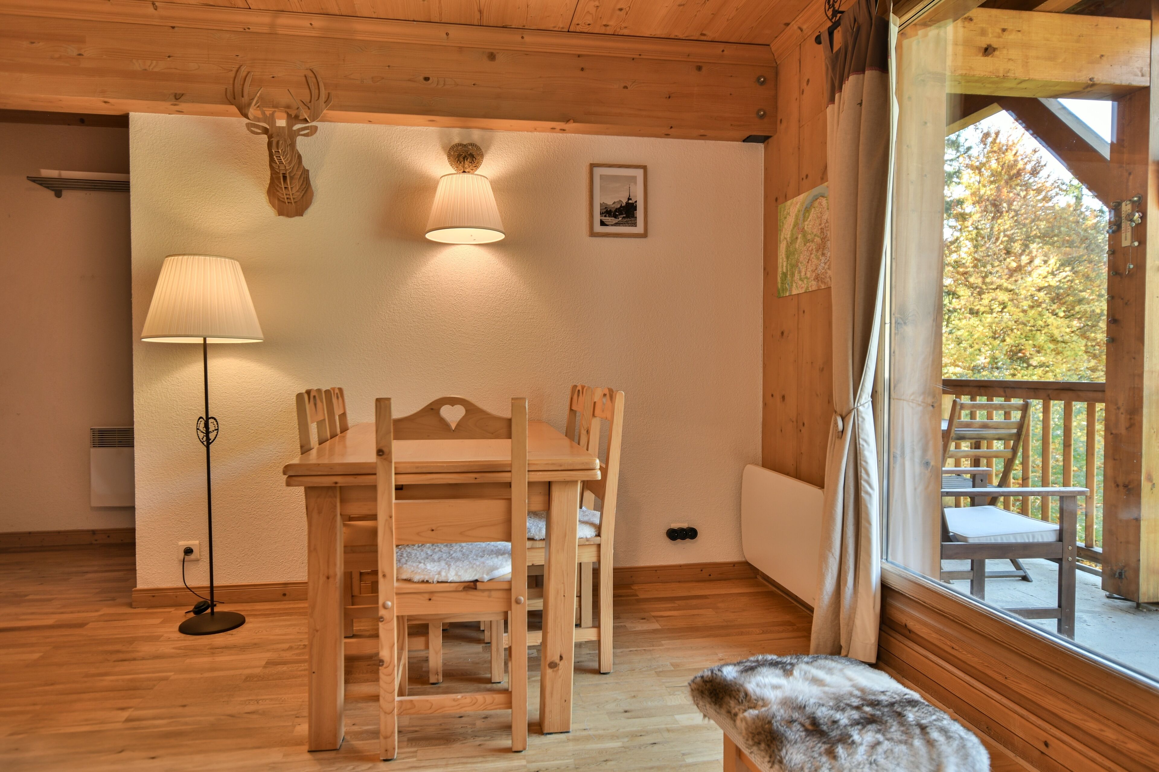 Un tavolo da pranzo in legno con sedie, una lampada e un cervo appeso al muro.