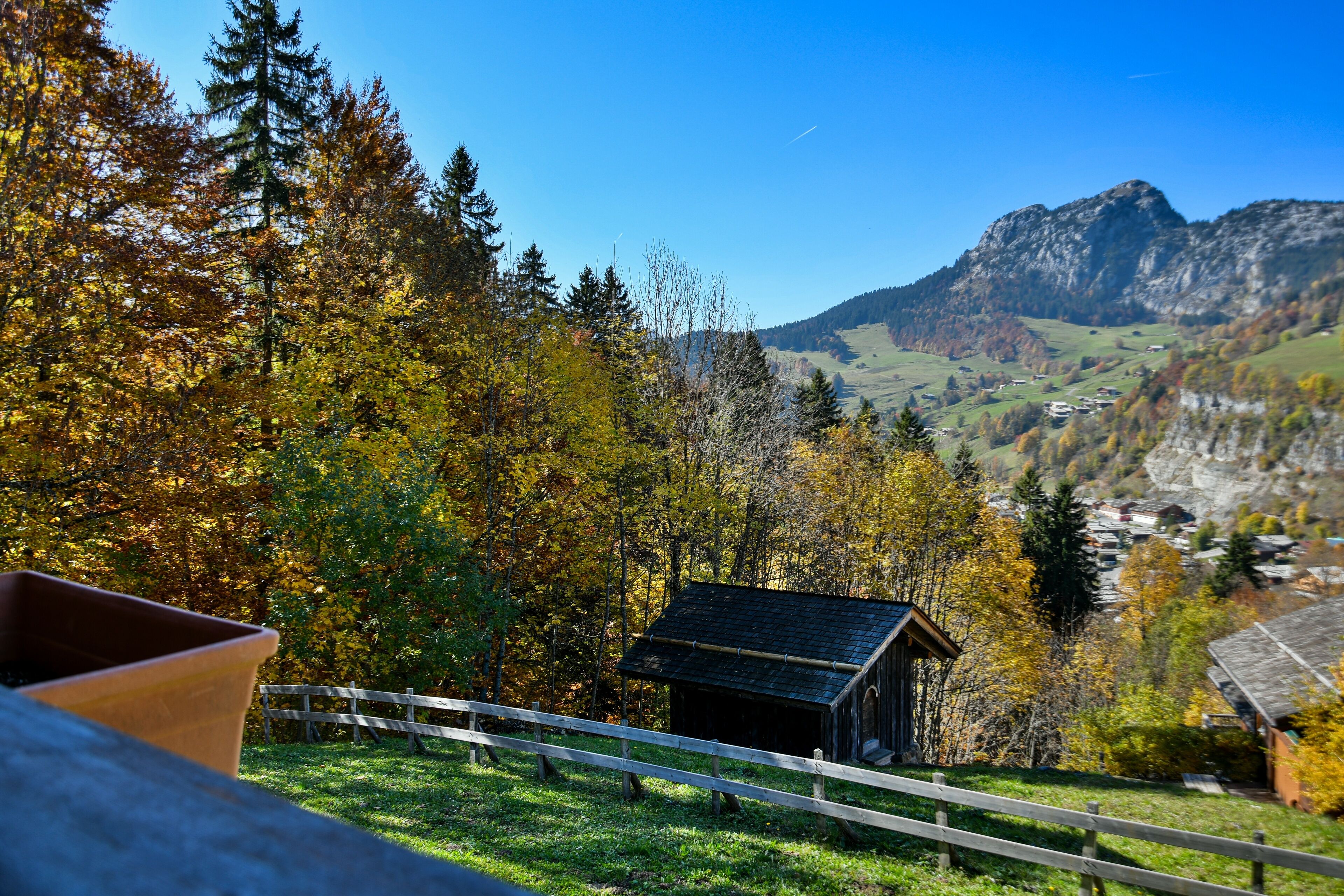 A rustic cabin with a wooden fence in a mountainous area.