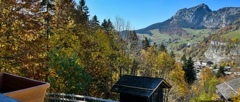 A rustic cabin with a wooden fence in a mountainous area.